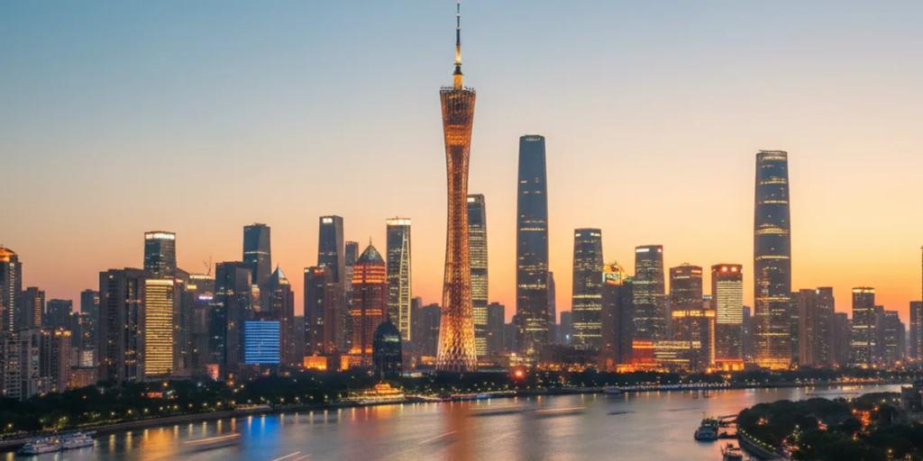Canton Tower glowing in color over the Pearl River at night, with the Zhujiang New Town skyline behind