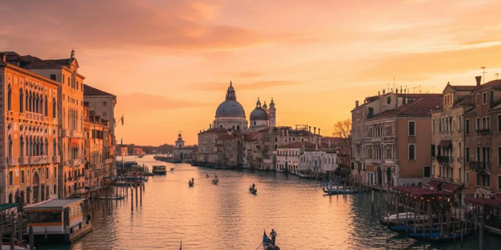 Gondolas moored on the Grand Canal at dusk with the domes of the Salute behind them